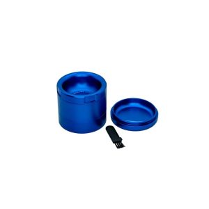 A blue metal grinder with its top removed, revealing "GRINDER" text inside, next to a small black brush.