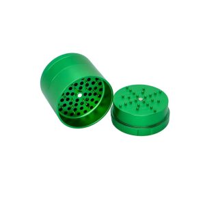 A bright green, two-piece metal grinder is open, revealing a perforated bottom and spiked top.