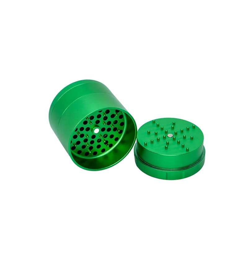 A bright green, two-piece metal grinder is open, revealing a perforated bottom and spiked top.