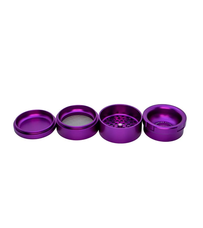 A four-piece purple metal grinder is disassembled and laid out horizontally on a white surface.