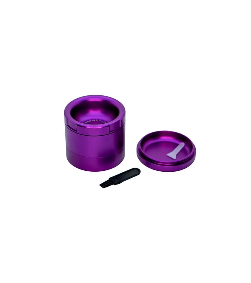 A purple metal grinder with a lid and a small black brush and white scraper on a white background.