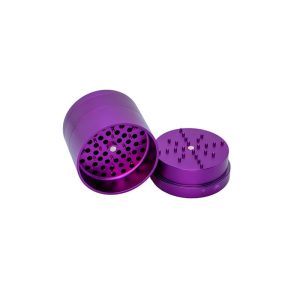 A purple metal grinder with its top removed, revealing sharp teeth and holes inside, on a white background.