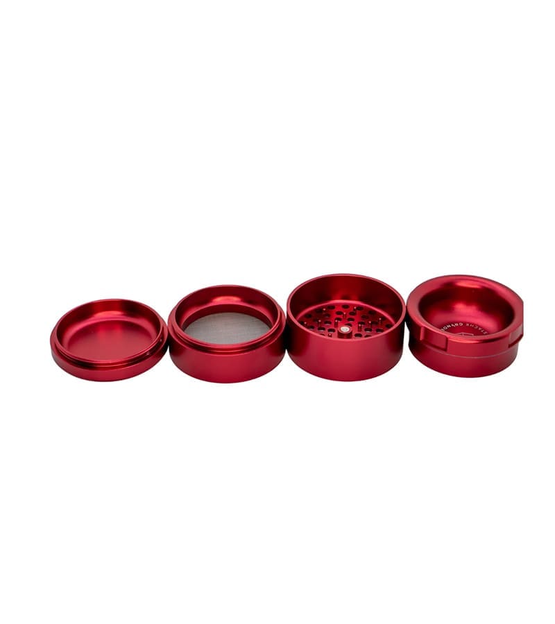 A four-piece, disassembled, glossy red metal grinder with a screen and sharp teeth, on a white background.