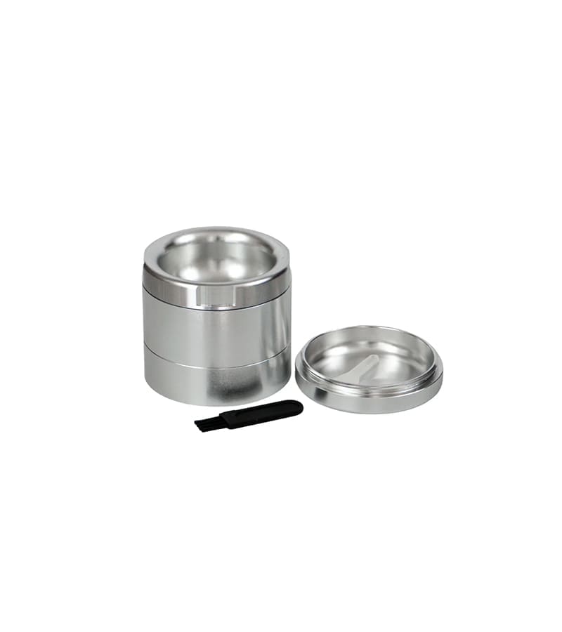 A three-piece silver metal grinder with a lid and a small black brush on a white background.