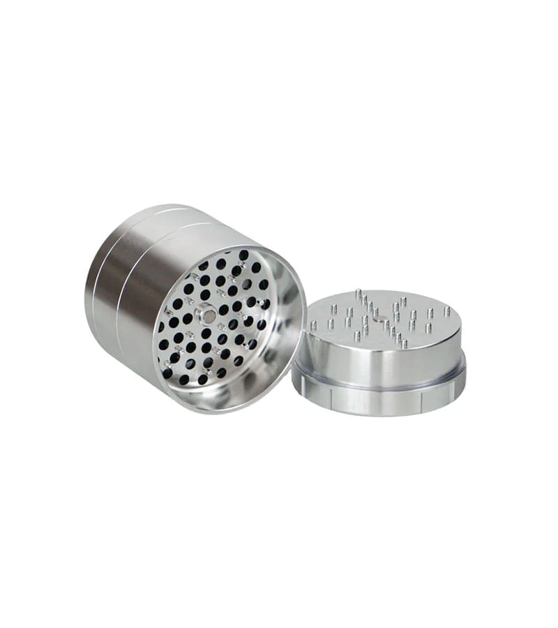 A silver metal grinder is open, showing a perforated bottom and a top with many small spikes.