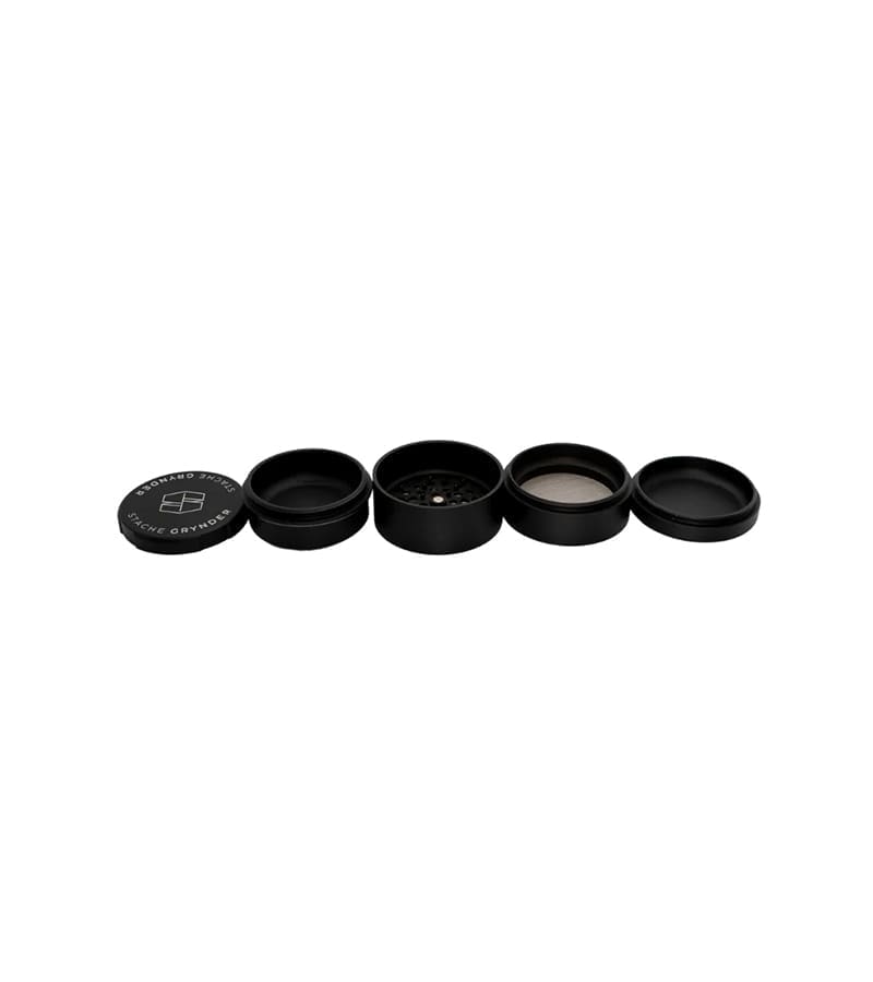 A black, cylindrical, four-piece herb grinder with "STACHE GRYNDER" and a logo on the lid.