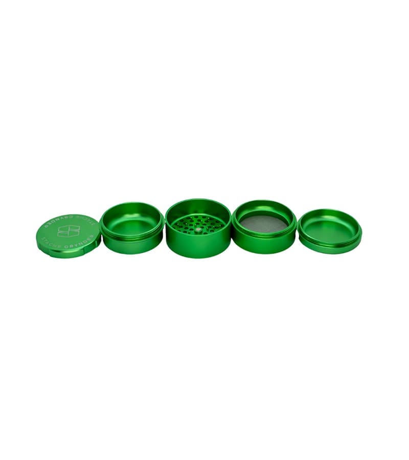 A four-piece green metal herb grinder is disassembled and laid out horizontally on a white background.