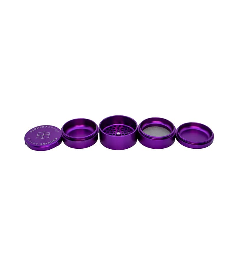 A disassembled purple metal grinder with "STACHE GRYNDER" embossed on the top lid, on a white background.
