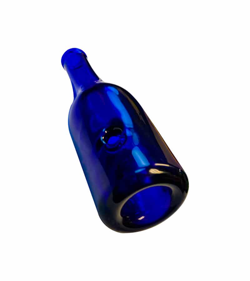 A dark blue glass bottle with a small circular indentation on its side lies diagonally against a white background.