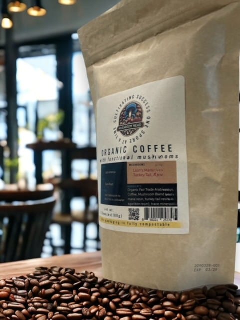 A bag of "ORGANIC COFFEE with functional mushrooms" sits on a pile of coffee beans in a cafe.