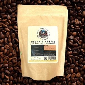 A light brown bag of "ORGANIC COFFEE with functional mushrooms" sits on a bed of dark roasted coffee beans.