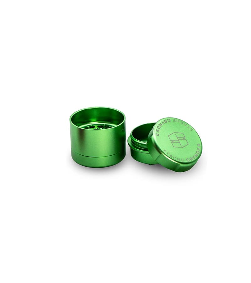 A bright green metal grinder with its top removed, displaying "GRYNDER" and "STACHE" text.