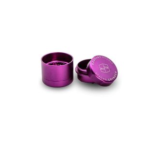 A purple metal grinder stands open, with the lid displaying "STACHE GRYNDER" and a logo.