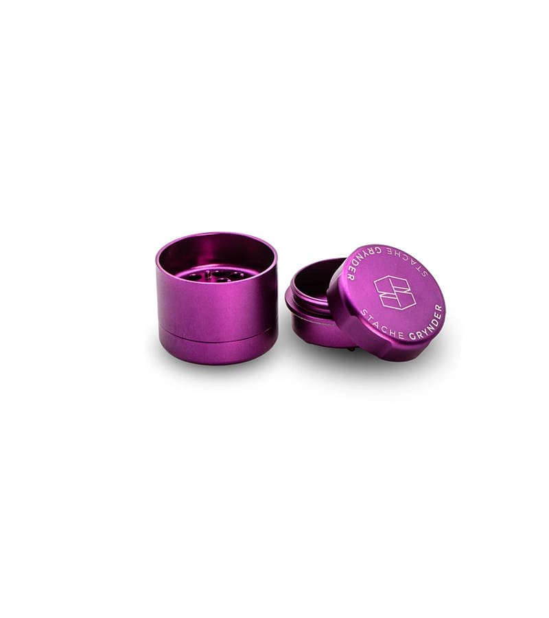 A purple metal grinder stands open, with the lid displaying "STACHE GRYNDER" and a logo.