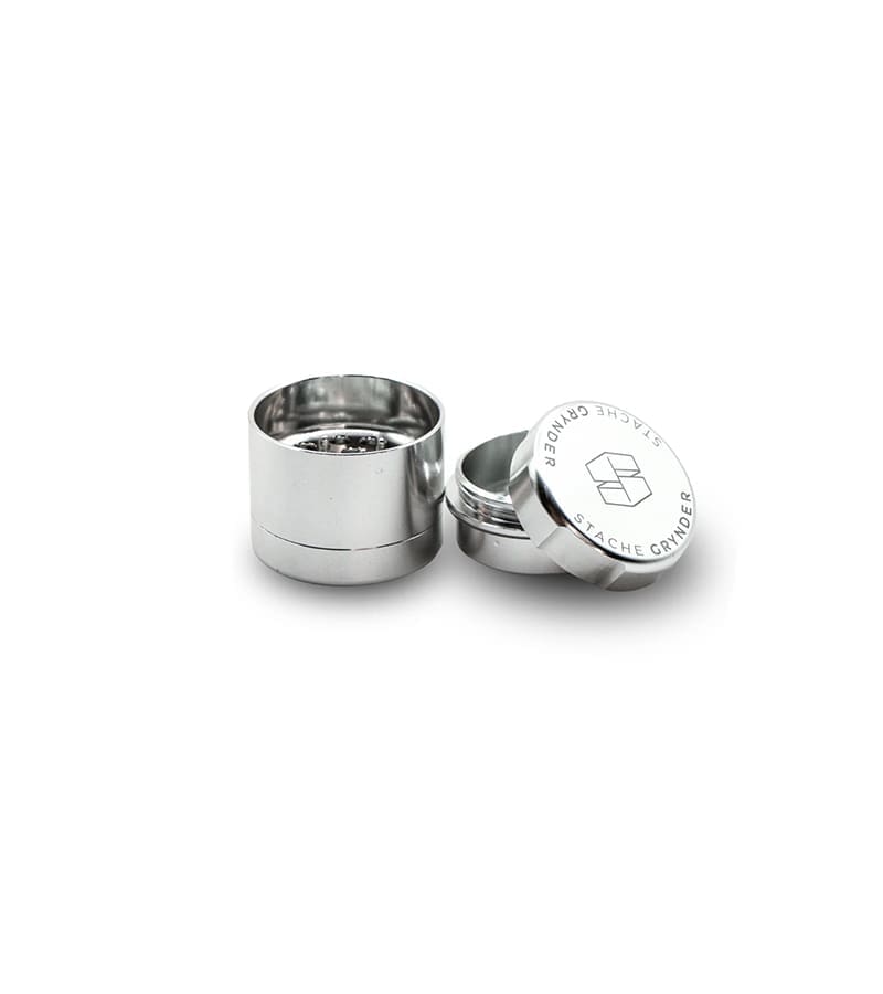 Two shiny silver metal grinders are shown, one open with "STACHE GRYNDER" and a logo on the lid.